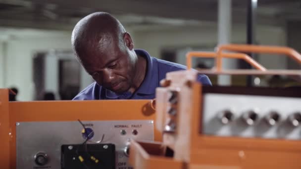 African Industrial Electrician Lucrează Unele Echipamente Industriale Portocalii — Videoclip de stoc