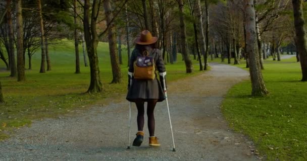 傷を負った女性歩くとともに松葉杖屋外 — ストック動画