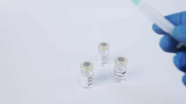 Hands testing syringe, anti covid 19 sars vaccine vials in background. Static, shallow focus
