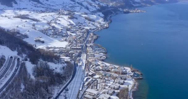 Nagy város, hójárta utakkal, melyek a központon keresztül futnak egy hideg téli napon a Walensee tónál. Drón piedesztális pásztázás lövés