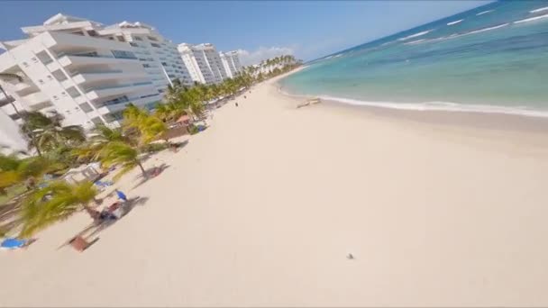 Menschen Schönen Weißen Sandstrand Gesäumt Von Hohen Kokosnussbäumen Und Apartmenthäusern — Stockvideo