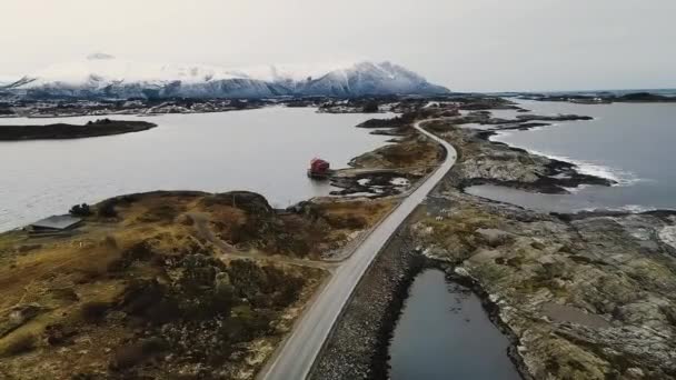 雪のアルプスを背景にノルウェーのスカルボイ島の大西洋道路 空中パンニング — ストック動画