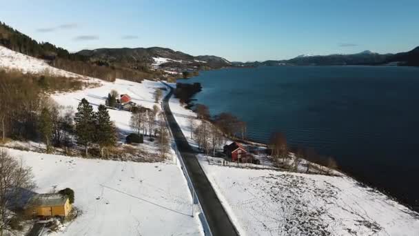 冬のノルウェーの雪景色に囲まれた海岸沿いの道路 — ストック動画