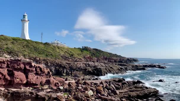 Farol Branco Fica Alto Acima Das Ondas Batendo Rochas Vermelhas — Vídeo de Stock