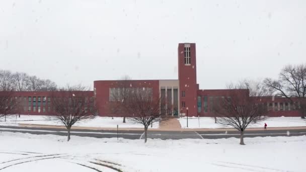 Rising drone air shot of large brick school, college, university during winter snow storm. Kurzy zrušeny pro studenty.