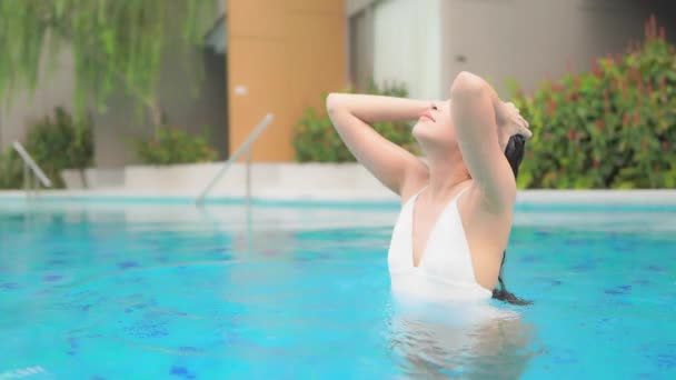 Csinos ázsiai nő a kék úszómedencében Érintés a nedves haj, teljes keret Lassú mozgás