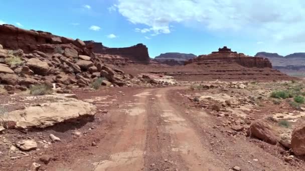 アメリカのサニーデーには砂岩の崖があるユタ砂漠の未舗装道路 傾きを上げる — ストック動画