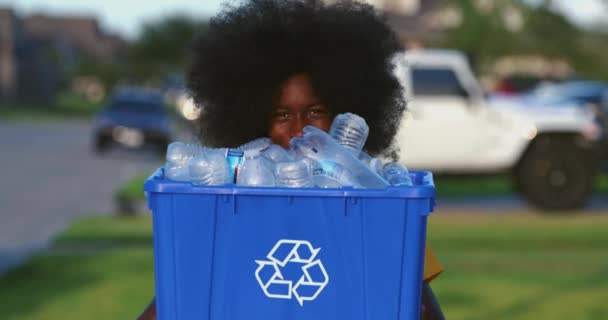 当他拿着装满塑料瓶的回收桶时 非洲裔美国青少年面带微笑 — 图库视频影像