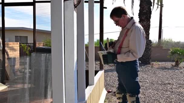Homeowner Brushing White Paint On Wooden Patio During House Construction. - medium shot