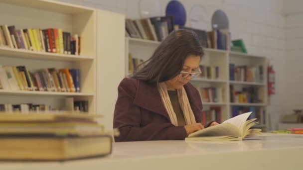 Mujer Mayor Con Gafas Libro Lectura Mesa Biblioteca Primer Plano — Vídeo de stock