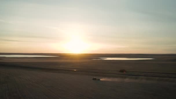 広大な農地で肥料を広げるトラクターの空中 ほこりの歩道 日没の背景 — ストック動画