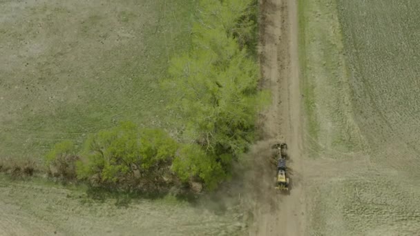 頭上道路緑の木の車線の横にほこりだらけの田舎道をレベリングする採点者 — ストック動画