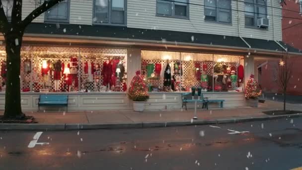 冬のウィンドウショッピング 雪が降ってる クリスマス休暇のために装飾された店構え マネキンと緑と赤の服 小さな町アメリカのシーン — ストック動画