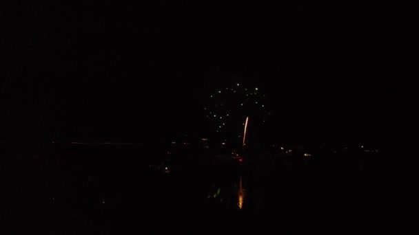 Dlouhý pomalu se pohybující klip, jak dron pomalu letí směrem k výbuchu ohňostroje show nad jezerem vidět krásné barvy v noci ve tmě. 4k 30fps.