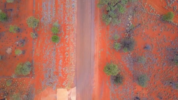Central Australian Outback. Shora dolů záběr, přes silnice, místní flóru a osady, s náklonem nahoru odhalit nízký hřeben. Natočeno na DJI Mavic Pro na velbloudí farmě poblíž Alice Springs.