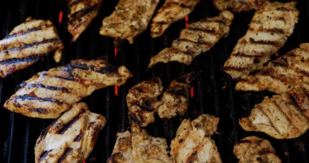 Chicken being perfectly charred or char grilled on electric grill with red heating element flames during summer barbecue, as camera quickly pans over meat and out. In Cinema 4K (4096x2160) 30fps.
