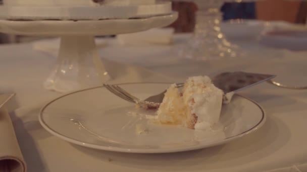 結婚式の席でテーブルの上にフォークでプレート上のケーキの半食白バニラ風味の作品 — ストック動画