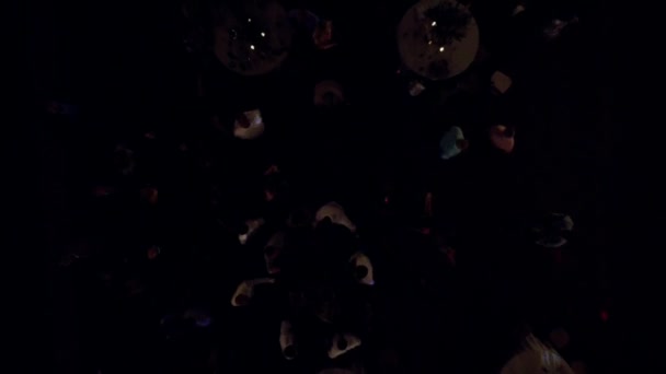 Felülről lefelé drónfelvétel egy csapat emberről, akik egy esküvői partin gyűltek össze este diszkó fényekkel.