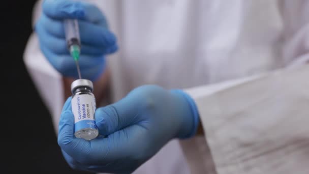 医者はCovid 19ワクチンのバイアルに注射針を挿入します — ストック動画