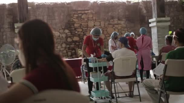 在菲律宾巴科罗德市一家有盖的健身房 一名当地女性志愿卫生工作者在计划的疫苗接种日期间 获得了一名老年男性的血压 — 图库视频影像