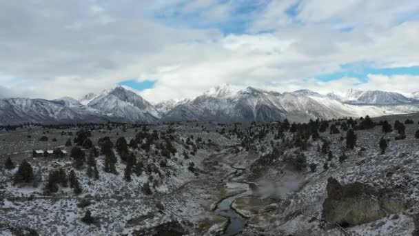 雪に覆われた風景と背景のシエラネバダ山脈と冬のマンモスレイクの温泉の空中ビュー カリフォルニア州 ドローンショット — ストック動画