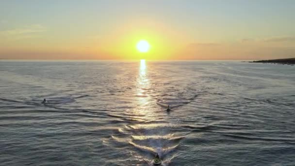背景に美しい夕日の間に海を巡航ジェットスキードライバー 空飛ぶ — ストック動画