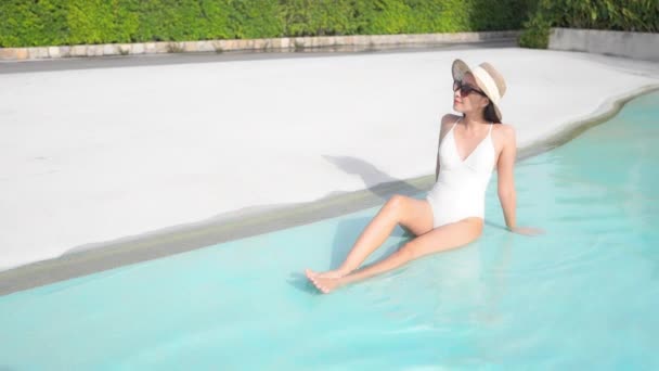 一个穿着泳衣和太阳帽的漂亮 健康的女人在一个度假胜地游泳池的浅水里放松了下来 标题空间 — 图库视频影像