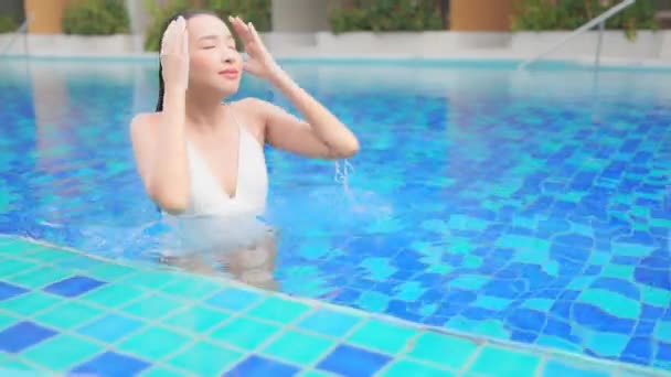 一位年轻女子从度假胜地的游泳池里出来后 抚平了长发 — 图库视频影像