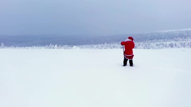 サンタクロースはラップランドの雪に覆われた高地で彼の棒で指摘 空中ドローンビュー — ストック動画