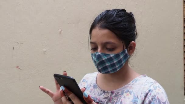 Привлекательная Женщина Маске Проверяет Телефон Стоя Возле Белой Стены Калькутта — стоковое видео