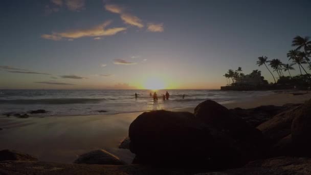 ハワイの砂浜で太平洋の波で遊ぶ人々の時間経過と背景に太陽が沈む — ストック動画