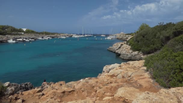 Cala Santandriaクリークの澄んだ水で泳ぐ観光客の風景海岸にドッキングヨット — ストック動画