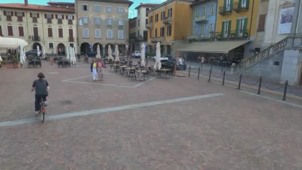 イタリアのArona Piazza Del Popolo広場で自転車に乗る女性の一人Povとバックビュー — ストック動画