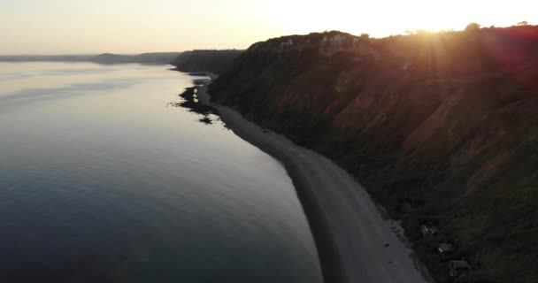 黄金の夕日の間にLittlecombeシュートビーチの横にある穏やかな静かな静かな水の空中ビュー — ストック動画