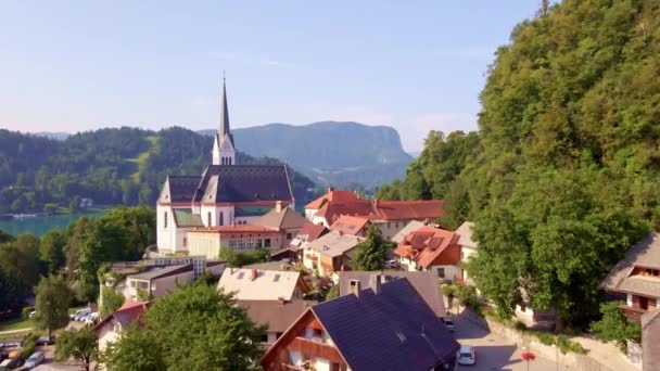 絵のように美しいスロベニアのアルパインの町と美しいセント マーティンス教区教会の上空からのプッシュインビュー — ストック動画