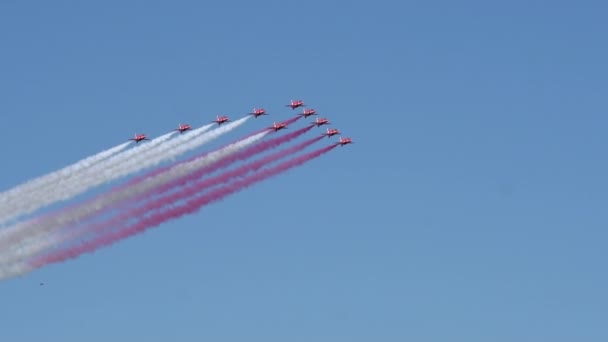 Red arrows flying in formation leaving smoke trails in sky