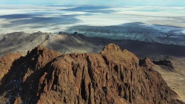 ドローンの砂漠の風景の上にある急なロッキー クリフBonnevilleでの晴れた日の空中ビュー塩のフラット — ストック動画