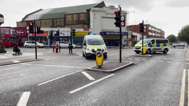 警察車両は交差点でコドンテープの後ろに引っ張り 警官は東ロンドンの殺人現場に出る — ストック動画