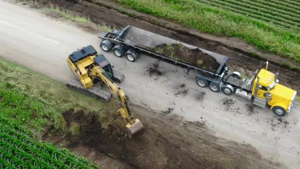 Koparka Wykopuje Żwir Wzdłuż Drogi Wyrzuca Dużej Przyczepie Wywrotki Bocznej — Wideo stockowe