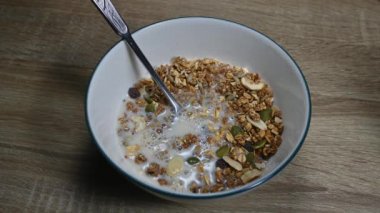 Kaşıklı granola ve baloncuk, tohum, kurutulmuş meyve ve sağlıklı kahvaltı yaparken badem sütü döküldü..