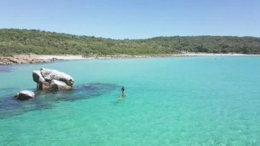 Paddleboard 'daki kadın Yallingup, Avustralya yakınlarındaki sahil şeridini keşfediyor.