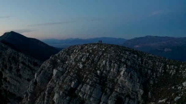 イタリアのカンパニア州で日没の間 岩の多い山の尾根を走っている2人の男性の周りの空中ビュー ドローンショット — ストック動画