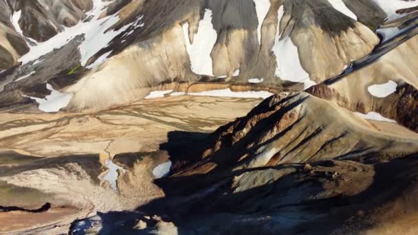 在冰岛五彩斑斓的陆地隆重山脉之间流过的一条冰河上漫步的峡谷 带着一个小小的远足者的轮廓 空中推进 向下倾斜相机运动 — 图库视频影像