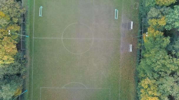电影直线下降的空中拍摄的足球场隐藏在绿色秋天的森林 空荡荡的足球场运动 健身的地点和目的地 — 图库视频影像