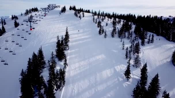 スキー場のケーブルウェイでドローンからのパノラマのトップビュー マウンテンリゾートの雪の冬の斜面にスキーヤーやスノーボーダーを運ぶスキーリフトエレベーター 多くの人々 Uhd 4Kビデオ — ストック動画