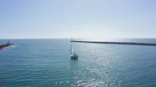 帆船在湾中的防波堤间航行 阳光反射在海面上 无人机视图 — 图库视频影像