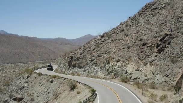 カリフォルニア砂漠の曲がりくねった山道でユーティリティトラックの空中ショット — ストック動画