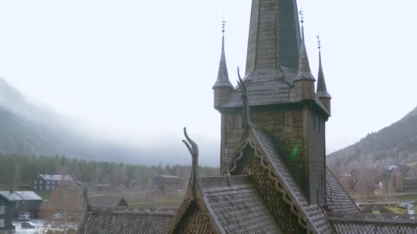 ノルウェーで霧の背景と雨が降っている間のLom Stave Churchの冒険的な眺め 空中ドローン撮影 — ストック動画