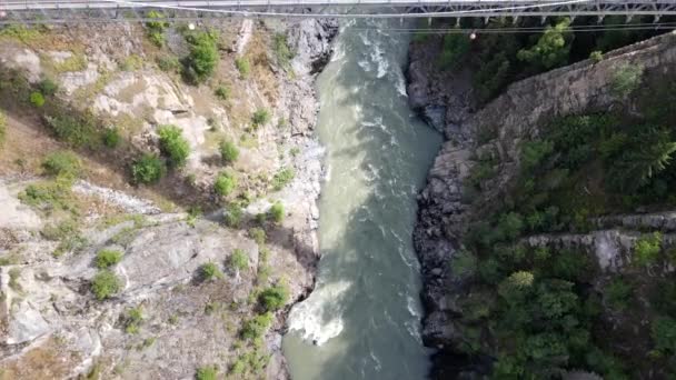 晴れた日にブリティッシュコロンビア州北部の底に氷河の川と渓谷の垂直上のダウンビュー ゆっくり前進ドローン映像明らかに高いHagwilget渓谷橋 — ストック動画