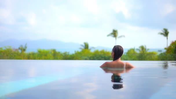 Una Donna Con Spalle Alla Telecamera Affaccia Una Piscina Resort — Video Stock